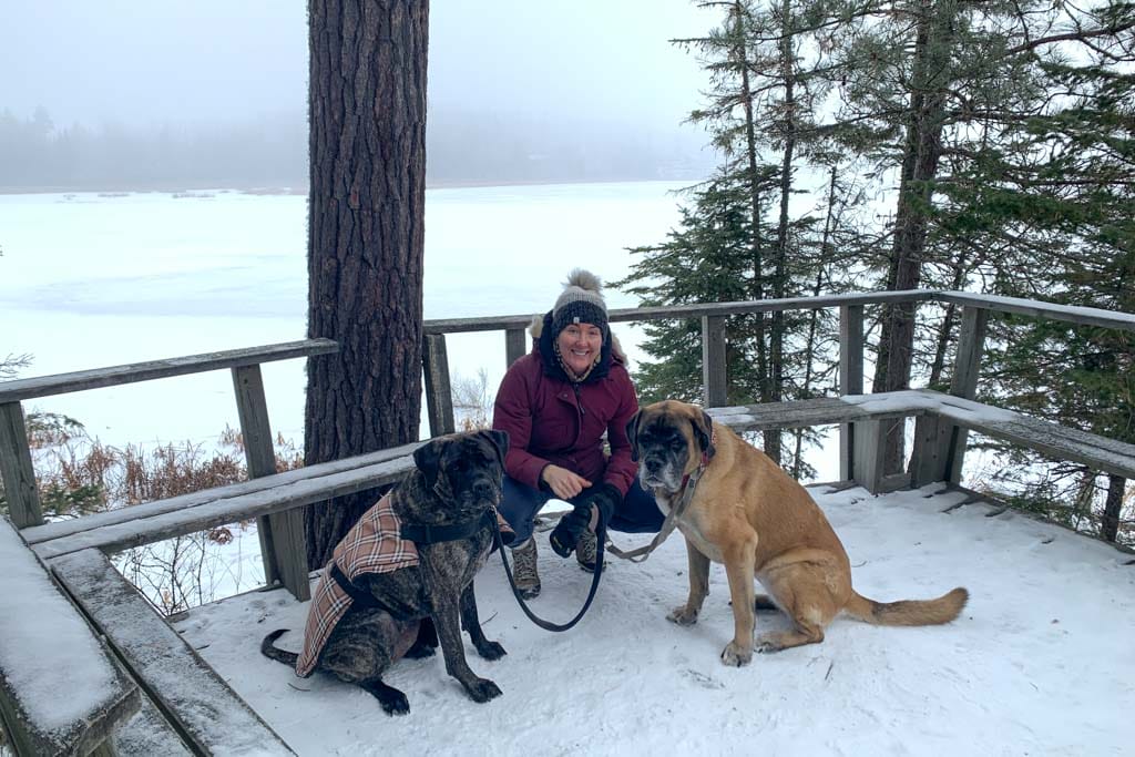 A woman poses with her dogs after an online workout including a hike in the Vernon Nature Area.
