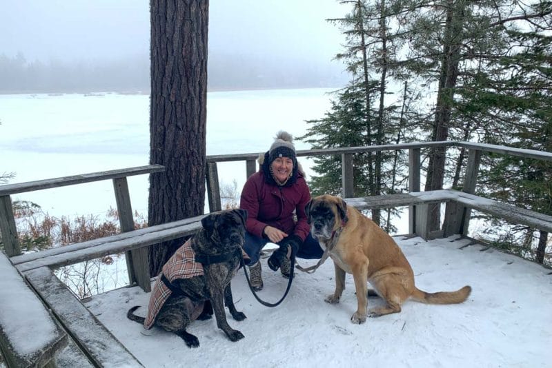 A woman poses with her dogs after an online workout including a hike in the Vernon Nature Area.