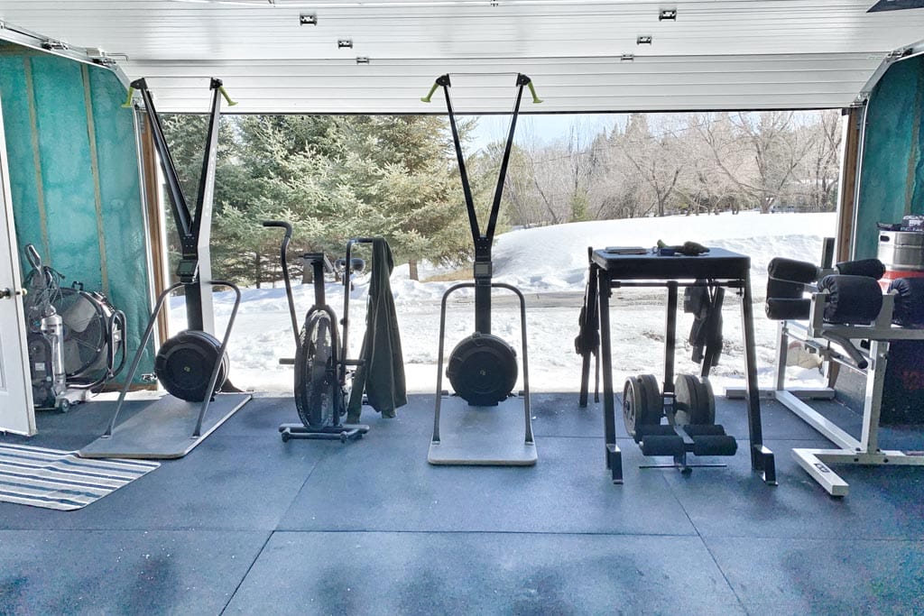A view from a garage gym with the overhead door lifted to show snowbanks in Kenora, Ontario.