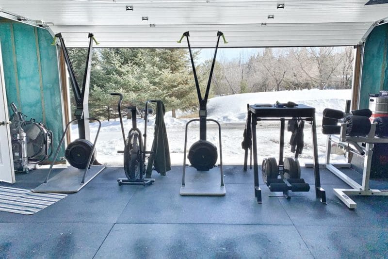 A view from a garage gym with the overhead door lifted to show snowbanks in Kenora, Ontario.